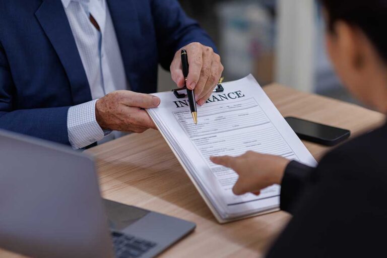 An insurance policy document with a credit report and calculator on a wooden table.